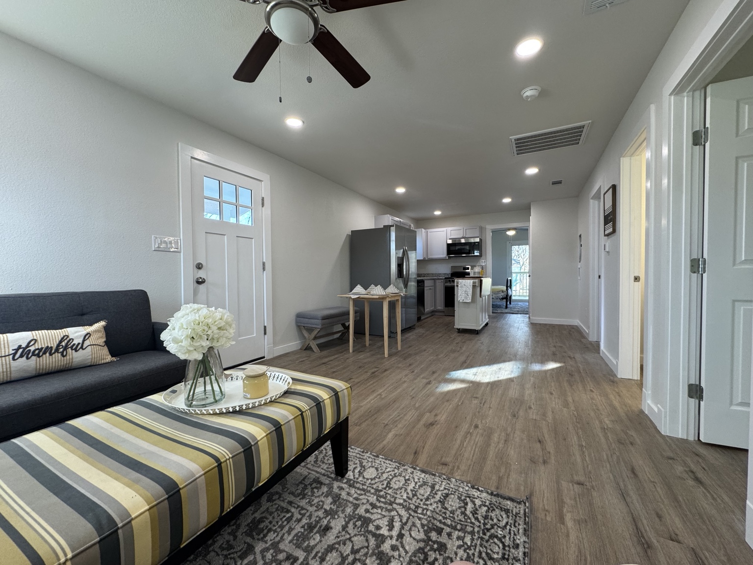 Completed renovation with an open living area, wood-look flooring, and a kitchen beyond
